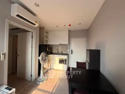 Modern compact kitchen with dining area and air conditioning in a cozy apartment.