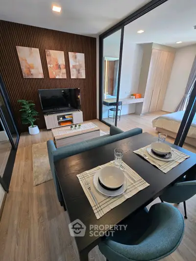 Modern living room with stylish decor and open layout to bedroom, featuring elegant dining setup.