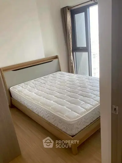Bright bedroom with large window and modern wooden bed frame, perfect for cozy living.