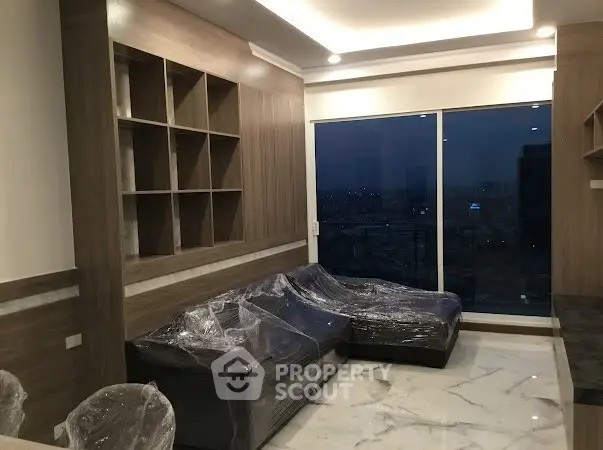 Modern living room with large window and city view, featuring sleek furniture and elegant lighting.