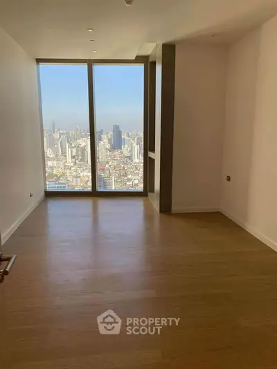 Spacious room with stunning city view through large floor-to-ceiling windows.