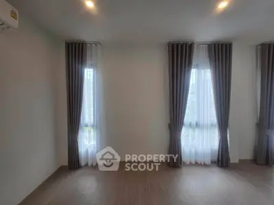Spacious room with elegant curtains and wooden flooring, perfect for modern living.