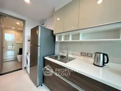 Modern kitchen with sleek cabinetry and stainless steel appliances, adjacent to a bathroom with washing machine.