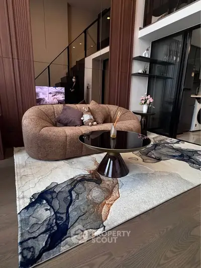 Luxurious modern living room with plush sofa, stylish coffee table, and artistic rug in a contemporary apartment.