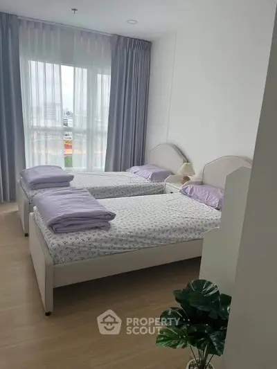 Bright twin bedroom with large window and modern decor in a stylish apartment.