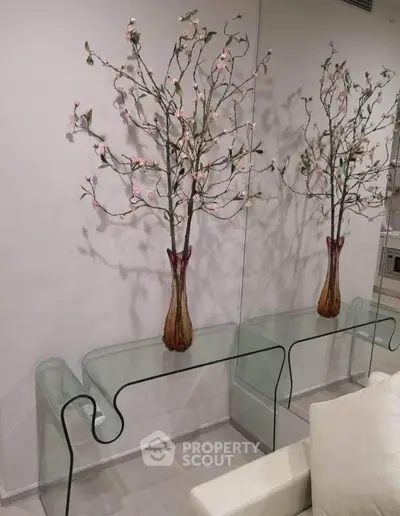 Elegant modern living room with glass console table and decorative floral arrangement.