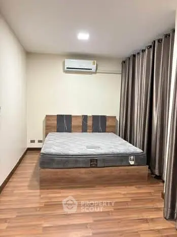 Modern bedroom with wooden flooring and air conditioning