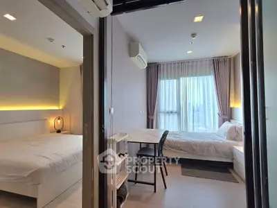 Modern bedroom with two beds, stylish decor, and large window offering natural light.