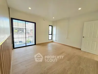 Spacious empty room with wooden flooring and large windows for natural light.