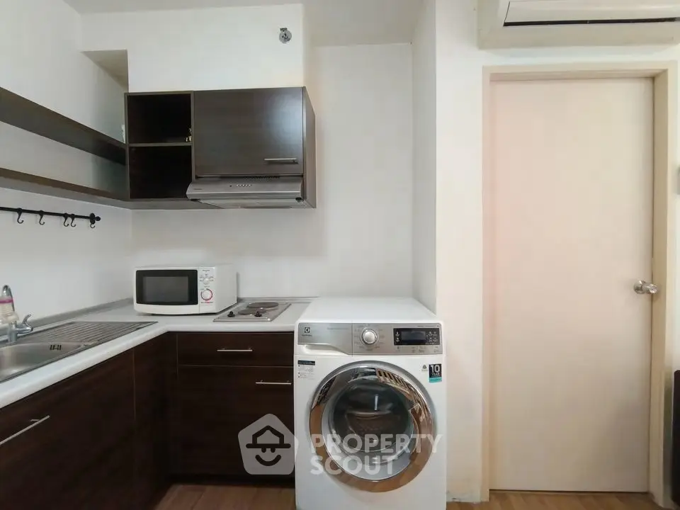 Modern kitchen with washing machine and microwave, sleek cabinetry, and efficient layout.