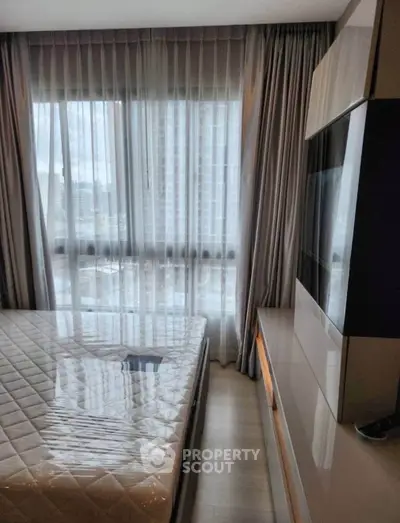 Modern bedroom with large window and sleek furniture in high-rise apartment.