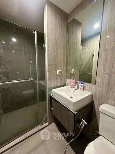 Modern bathroom with glass shower and sleek fixtures in contemporary design.