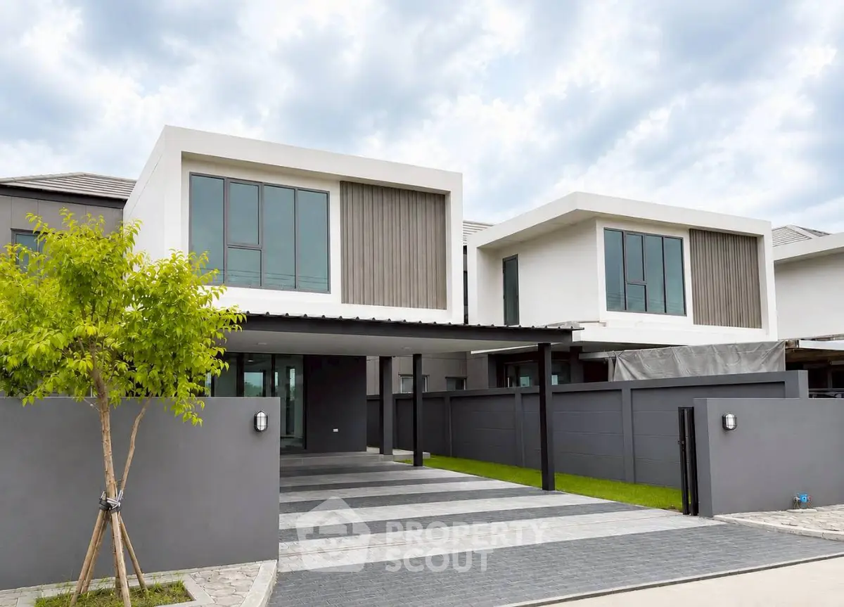 Modern two-story house with sleek design and spacious driveway in a serene neighborhood.