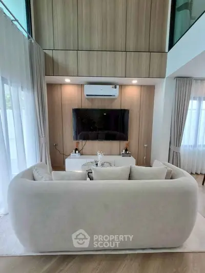 Modern living room with elegant sofa, wall-mounted TV, and stylish wood paneling.