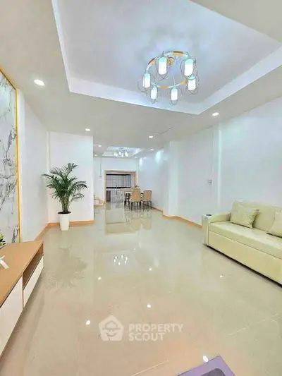 Spacious modern living room with elegant chandelier and sleek tile flooring.