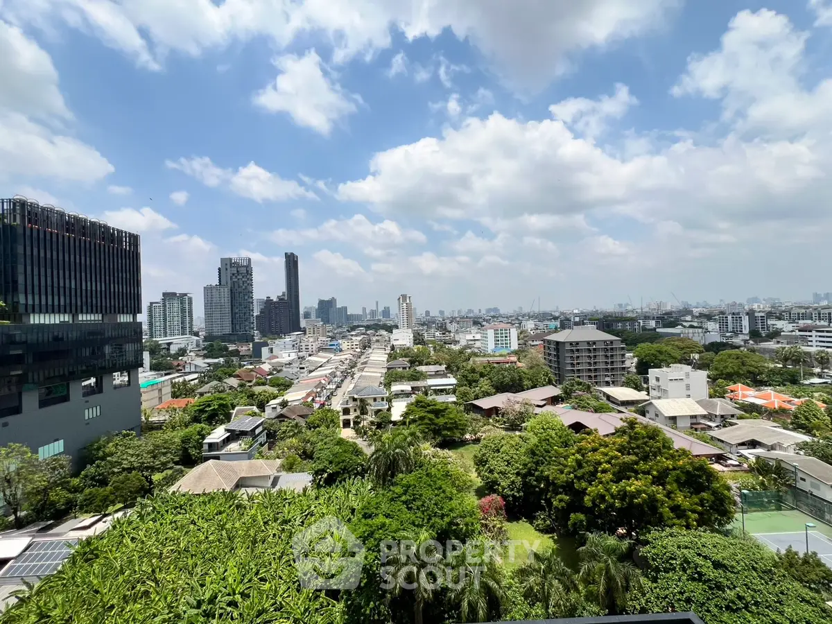Stunning cityscape view from a high-rise building showcasing urban skyline and lush greenery.
