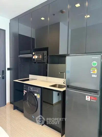 Modern kitchen with sleek black cabinets, built-in appliances, and washing machine