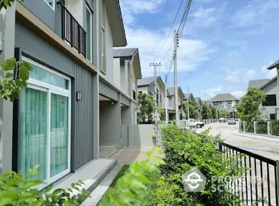 Modern townhouse exterior with lush greenery and clear blue sky