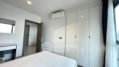 Modern bedroom with sleek white wardrobe and air conditioning in a bright apartment.
