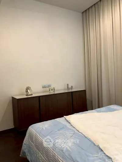Cozy bedroom with elegant decor and soft lighting, featuring a stylish cabinet and comfortable bedding.