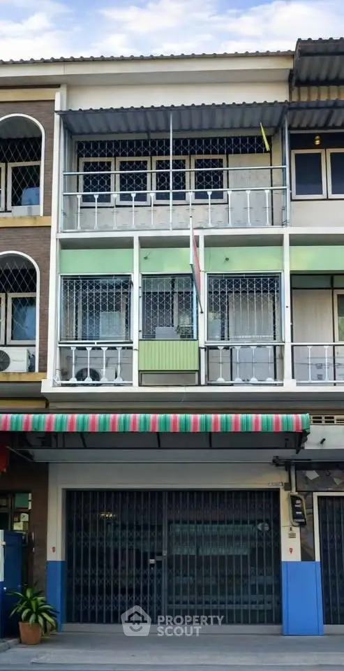 Charming multi-story building with colorful awning and secure gated entrance, ideal for urban living.