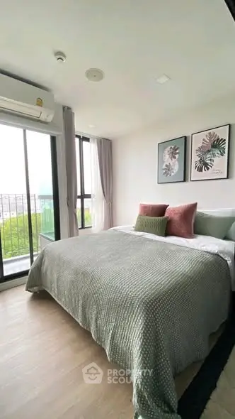 Cozy bedroom with stylish decor and large window offering natural light and city view.