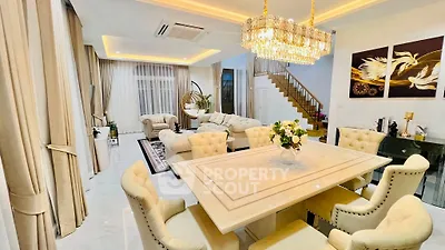 Luxurious open-plan living and dining area with elegant chandelier and plush seating.