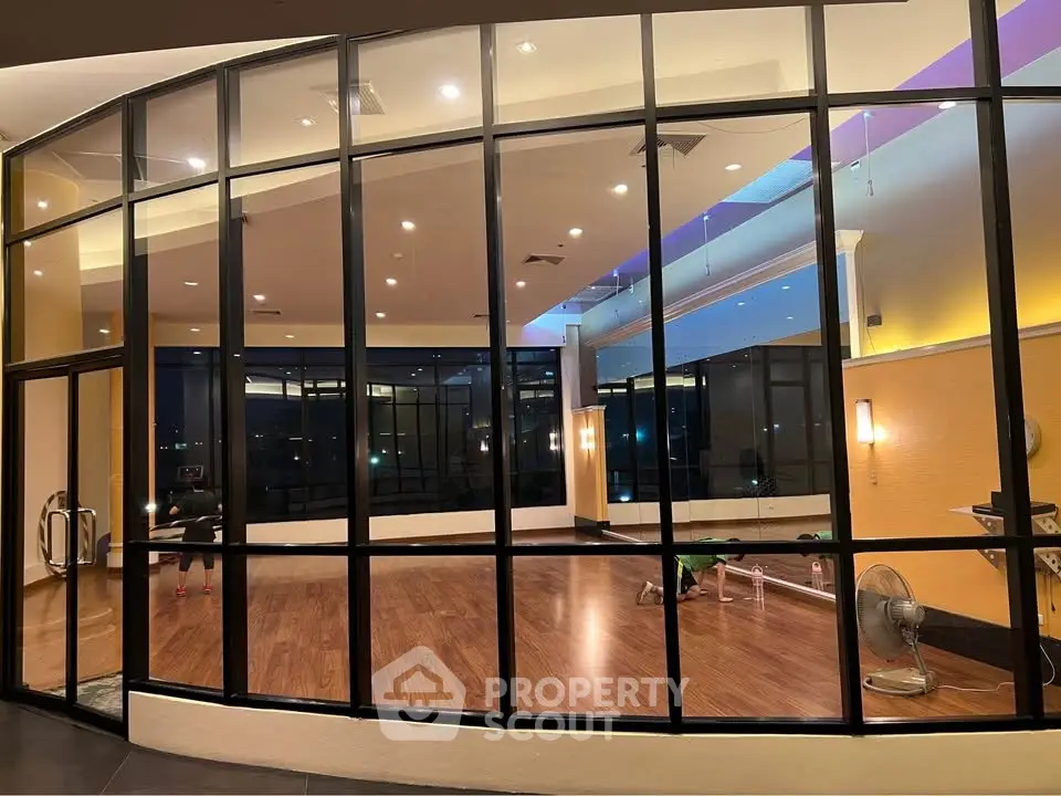 Spacious gym with floor-to-ceiling windows and modern lighting in a luxury building.