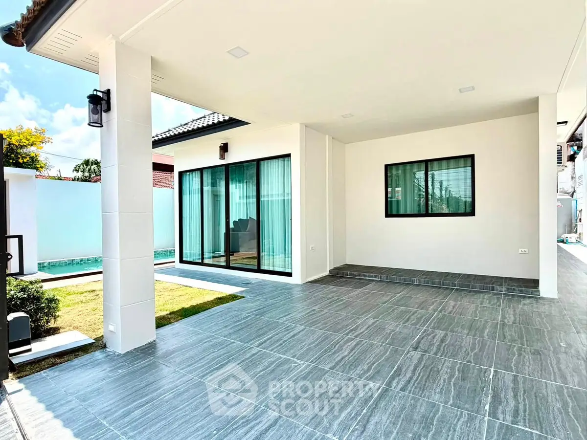 Modern home exterior with spacious tiled patio and large sliding glass doors.