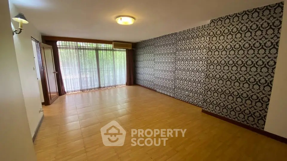 Spacious living room with patterned accent wall and large windows for natural light.
