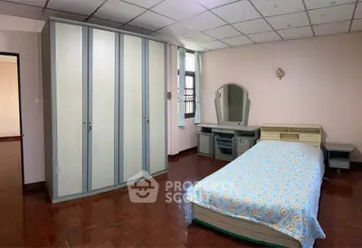 Spacious bedroom with wooden flooring and ample storage space