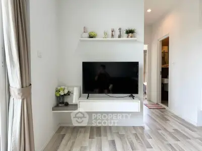 Modern living room with wall-mounted TV and stylish decor in a bright apartment.