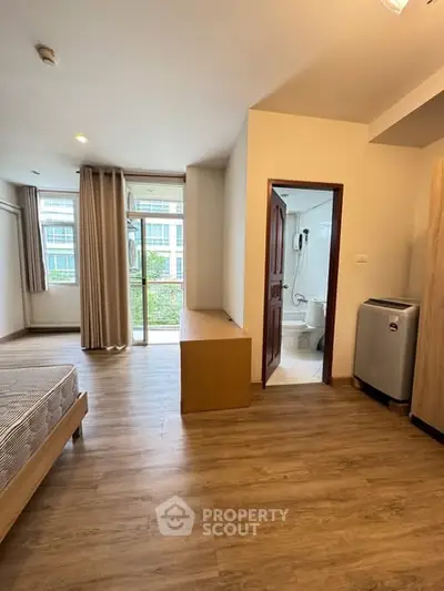 Spacious bedroom with wooden flooring and balcony access in modern apartment