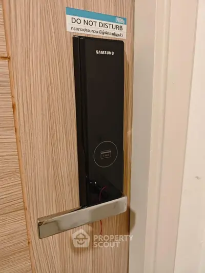 Modern electronic door lock on wooden door with do not disturb sign