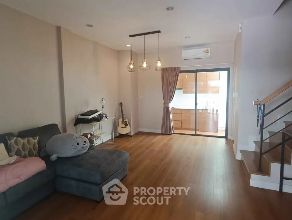 Spacious living room with modern decor and wooden flooring, featuring cozy sofa and stylish lighting.