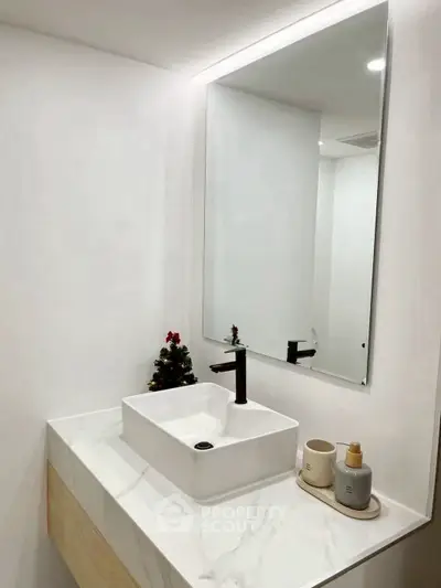 Modern minimalist bathroom with sleek white sink and stylish black faucet