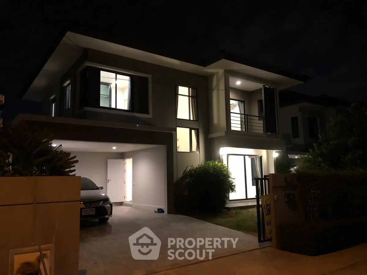 Modern two-story house with illuminated windows and driveway at night