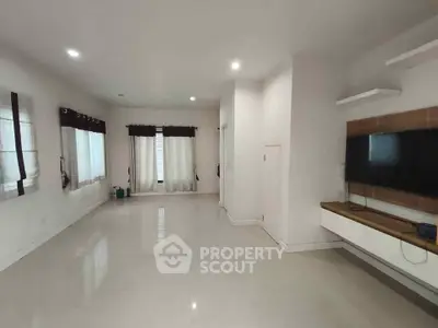 Spacious living room with modern TV setup and large windows for natural light.