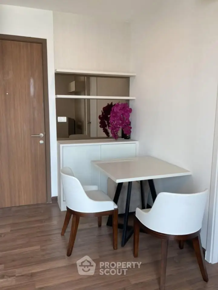 Modern dining area with wooden flooring and stylish white chairs in a cozy apartment.