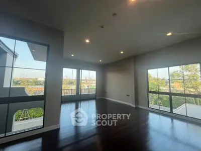 Spacious living room with large windows and hardwood floors offering natural light and scenic views.