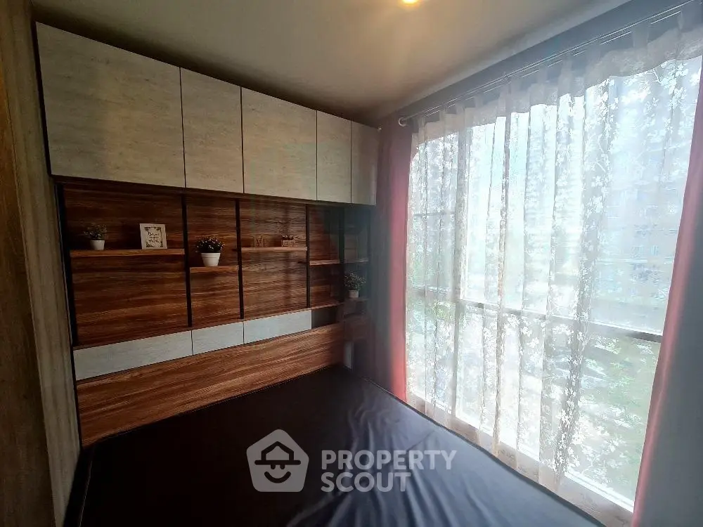Cozy bedroom with large window and modern wooden cabinetry