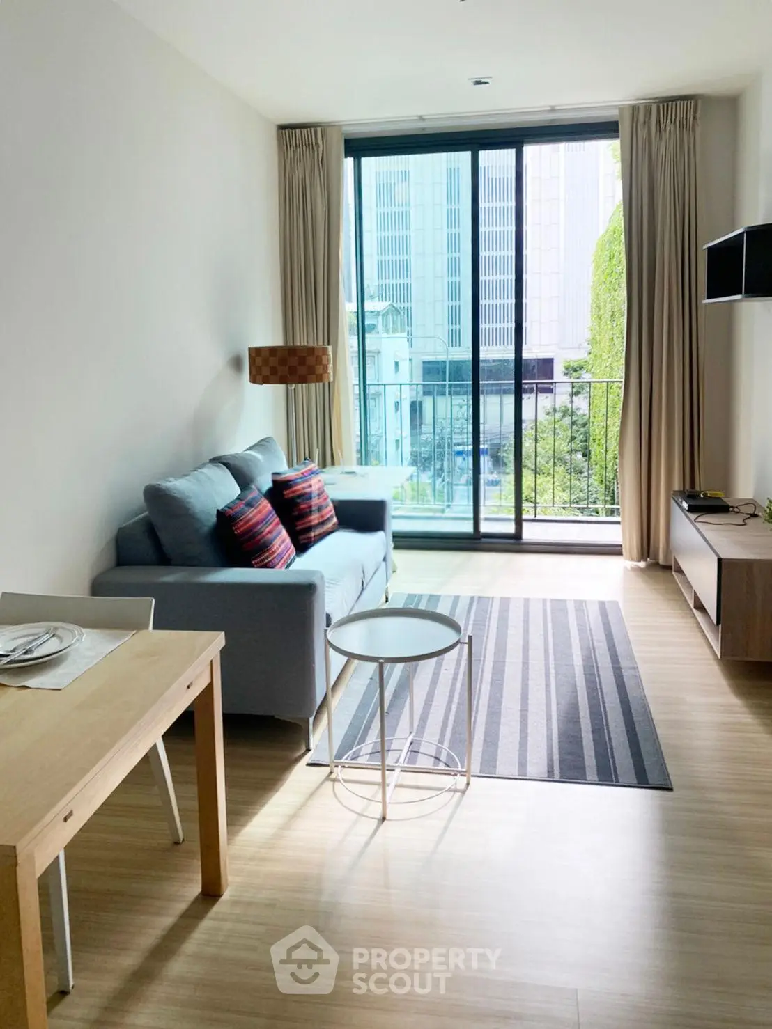 Modern living room with large windows and city view, featuring cozy sofa and stylish decor.