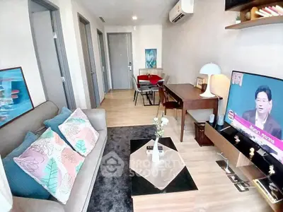 Modern living room with stylish decor and cozy seating area, featuring a wall-mounted TV and air conditioning.