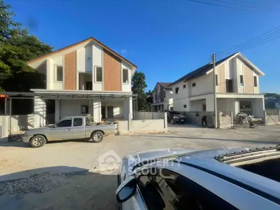 Modern residential houses with spacious driveways and clear blue sky.
