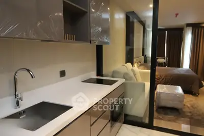 Modern open-layout kitchen with sleek design leading to a cozy bedroom in a stylish apartment.