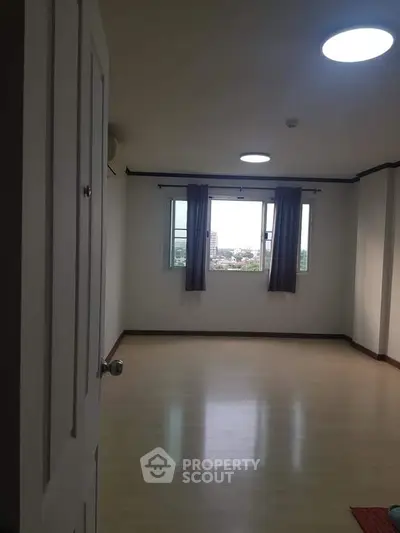 Spacious empty room with large windows and wooden flooring, ideal for customization.