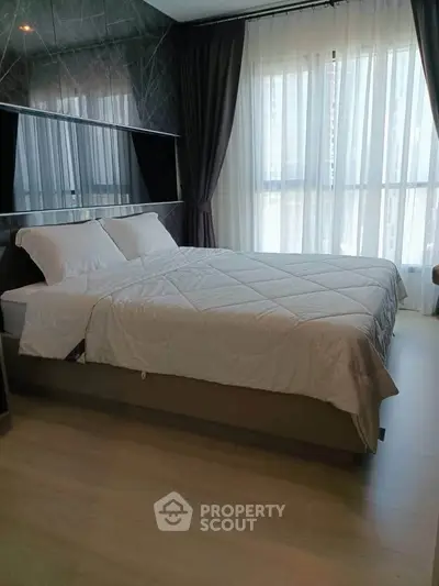 Spacious bedroom with modern decor and large window offering natural light.
