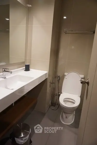 Modern bathroom with sleek fixtures and neutral tones, featuring a spacious sink and toilet.