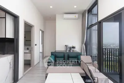 Modern living room with large windows and city view, featuring stylish furniture and open layout.