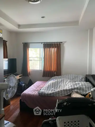 Cozy bedroom with natural light, wooden flooring, and modern furnishings for a comfortable living experience.